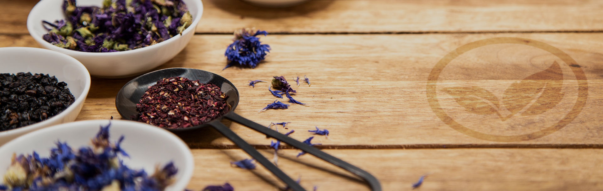 dried blue and purple flowers, dark berries and a red tea blend are beautifully arranged in bowls